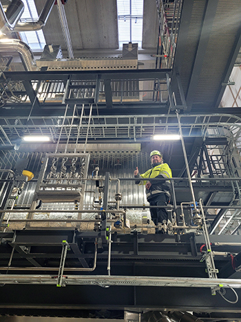 Mika Alén i gula skyddskläder på trappavsats inne på kraftvärmeverket Salzburg 2, BBP Valmet